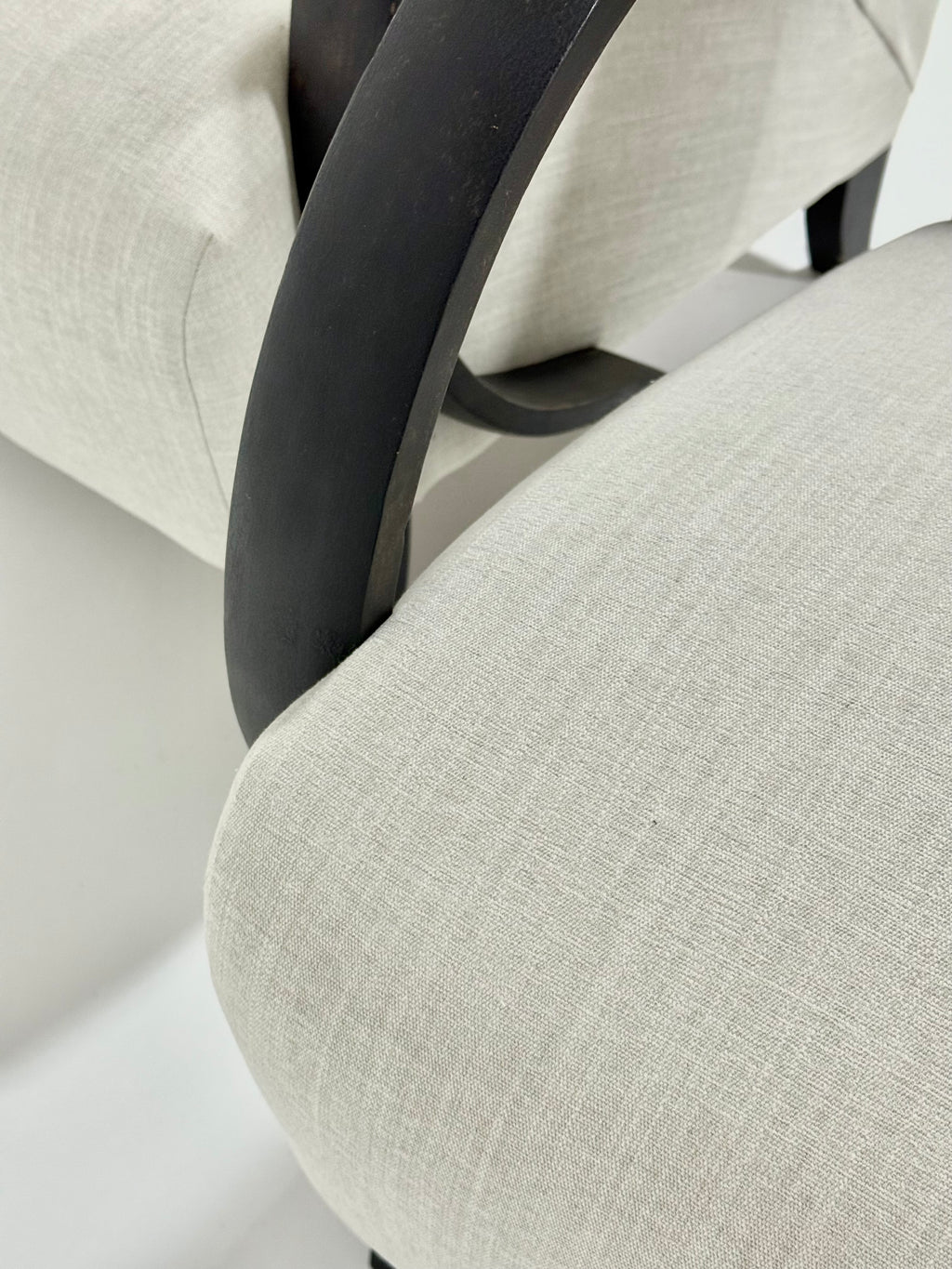Close-up of a chair with beige fabric and black wood frame.