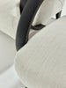 Close-up of a chair with beige fabric and black wood frame.