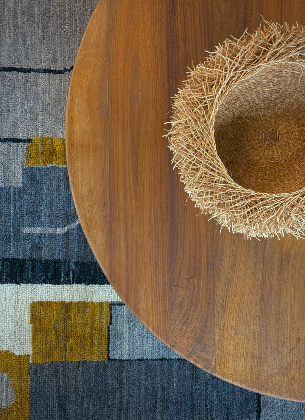 Wooden table with a straw hat on a patterned rug