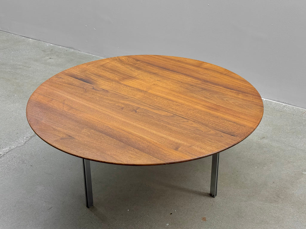 Round wooden table with metal legs on a concrete floor.