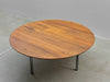 Round wooden table with metal legs on a concrete floor.