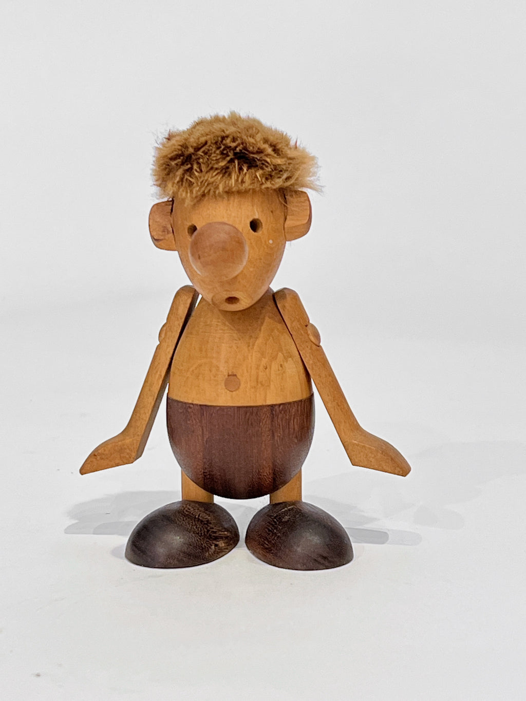 Wooden figurine of a stylized human-like character with a fur hair on a white background