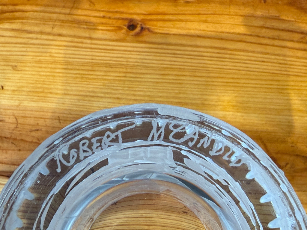 Close-up of a glass object with engraved signature of the maker