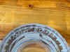 Close-up of a glass object with engraved signature of the maker