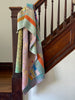 Colorful kantha stitched quilt draped over a wooden staircase
