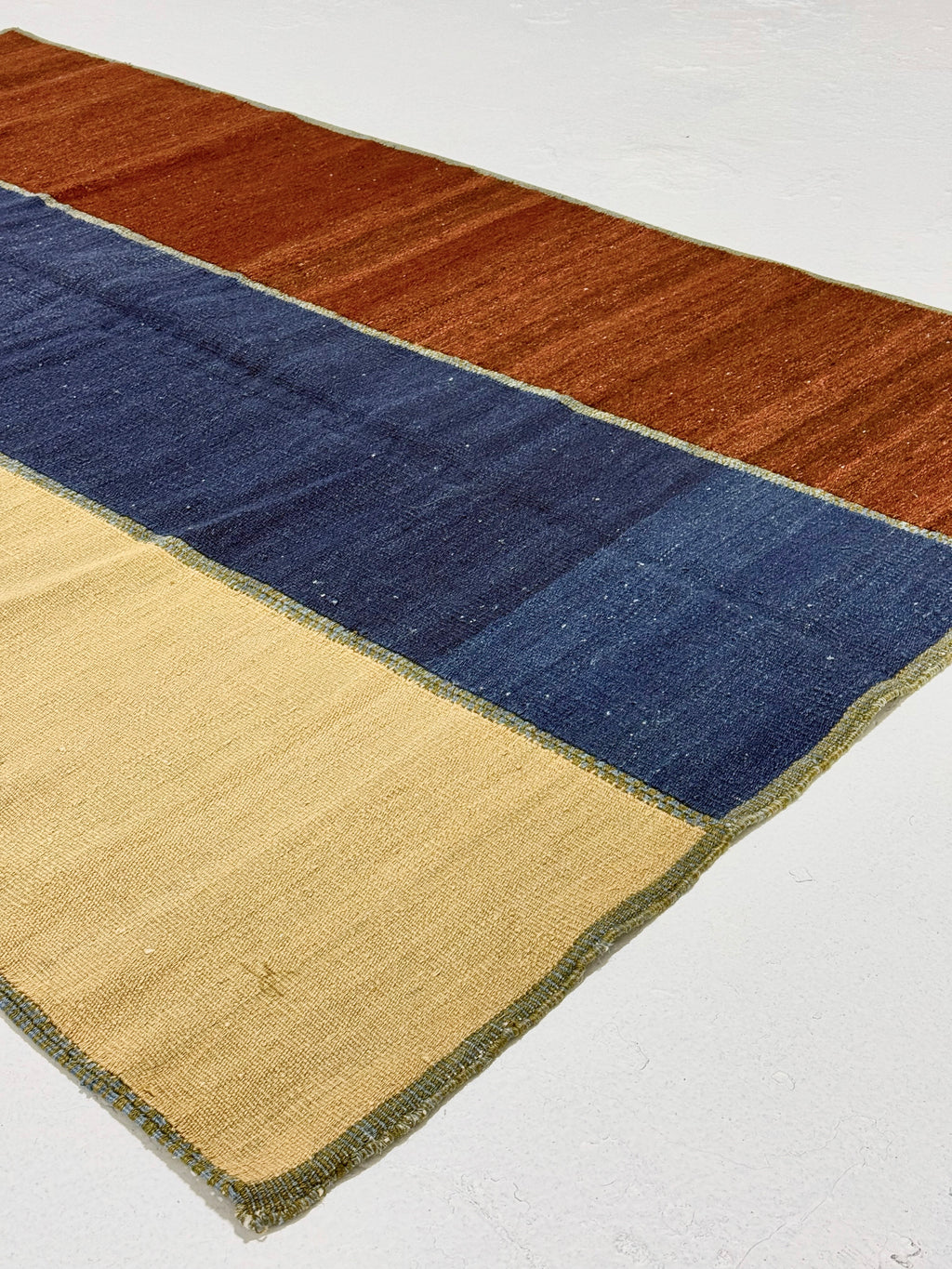 Color-blocked rug with brown, blue, and beige sections on a white background