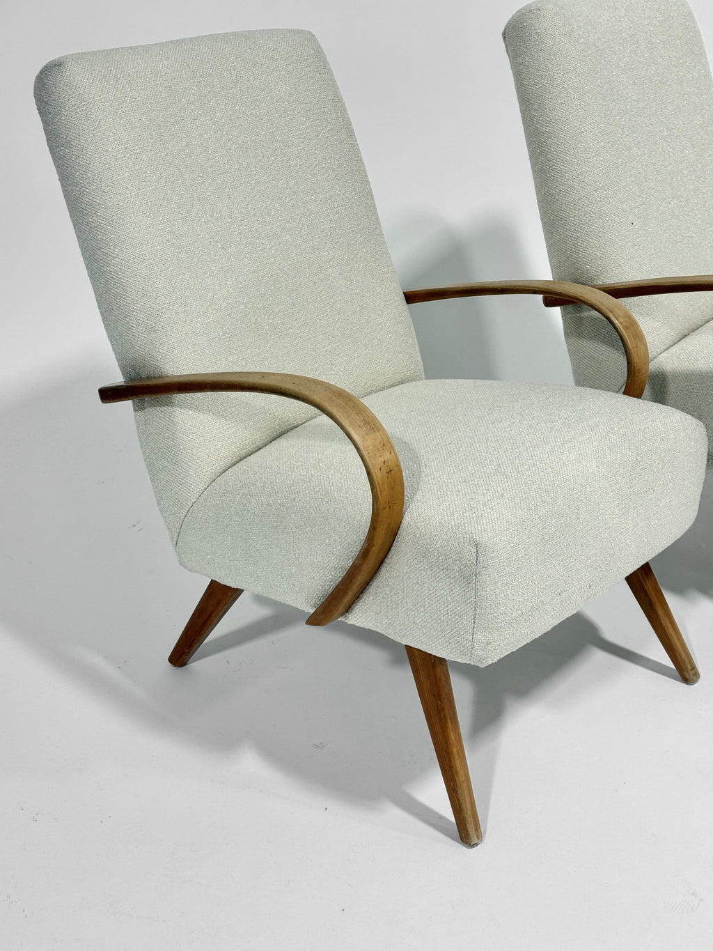 Light gray armchair with wooden armrests and legs on a white background