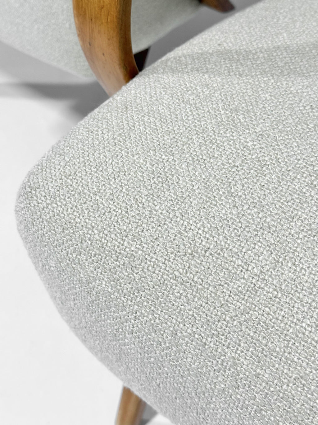 Close-up of a textured gray chair with wooden legs on a light background