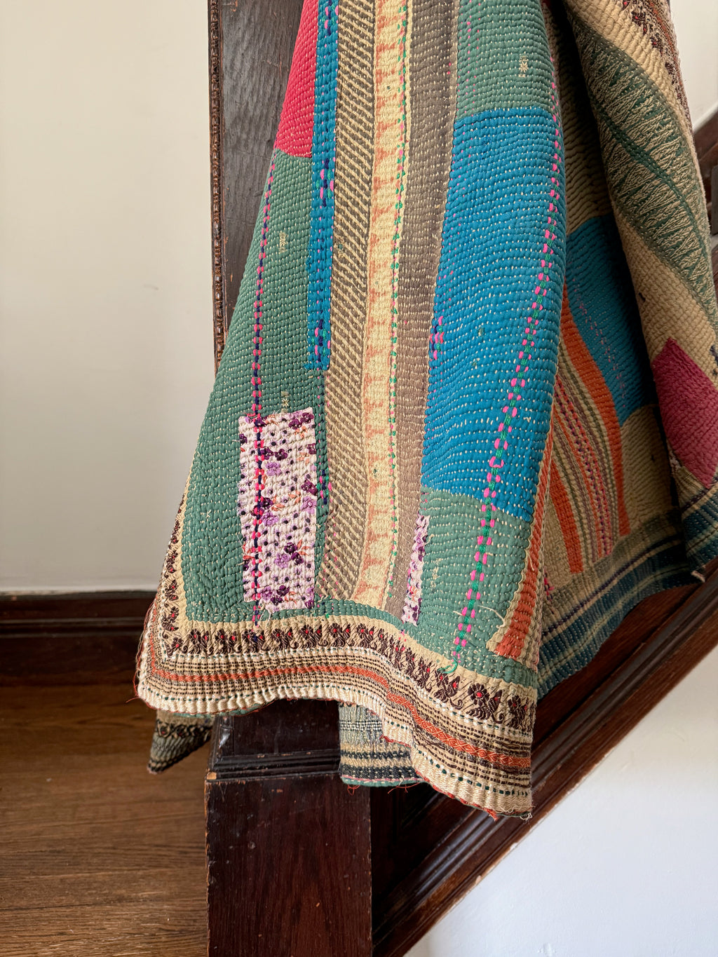 Multicolored quilt draped over a wooden surface with a neutral background