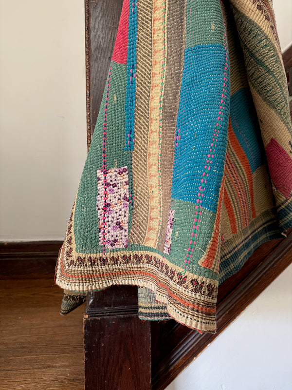 Multicolored quilt draped over a wooden surface with a neutral background