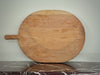 Large wooden pizza peel on a marble floor with a neutral wall background