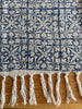 Close-up of a patterned blanket with tassels on a wooden surface