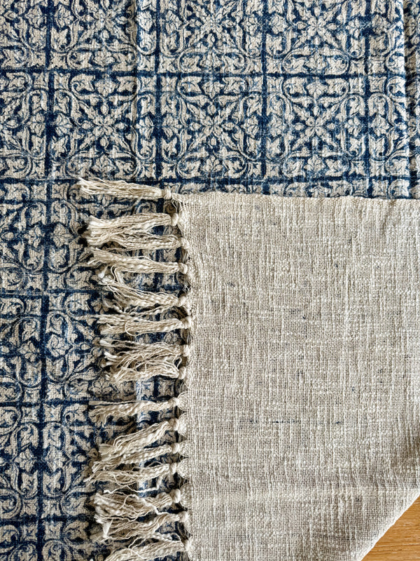 Close-up of a textured rug with geometric pattern and fringed edge.