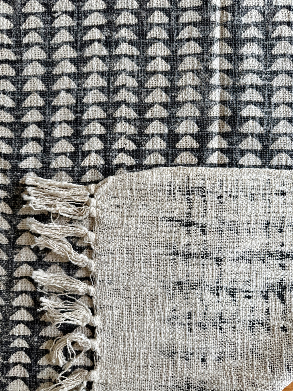 Textured fabric with geometric pattern and tassels on a black and white checkered background