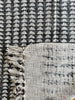 Textured fabric with geometric pattern and tassels on a black and white checkered background