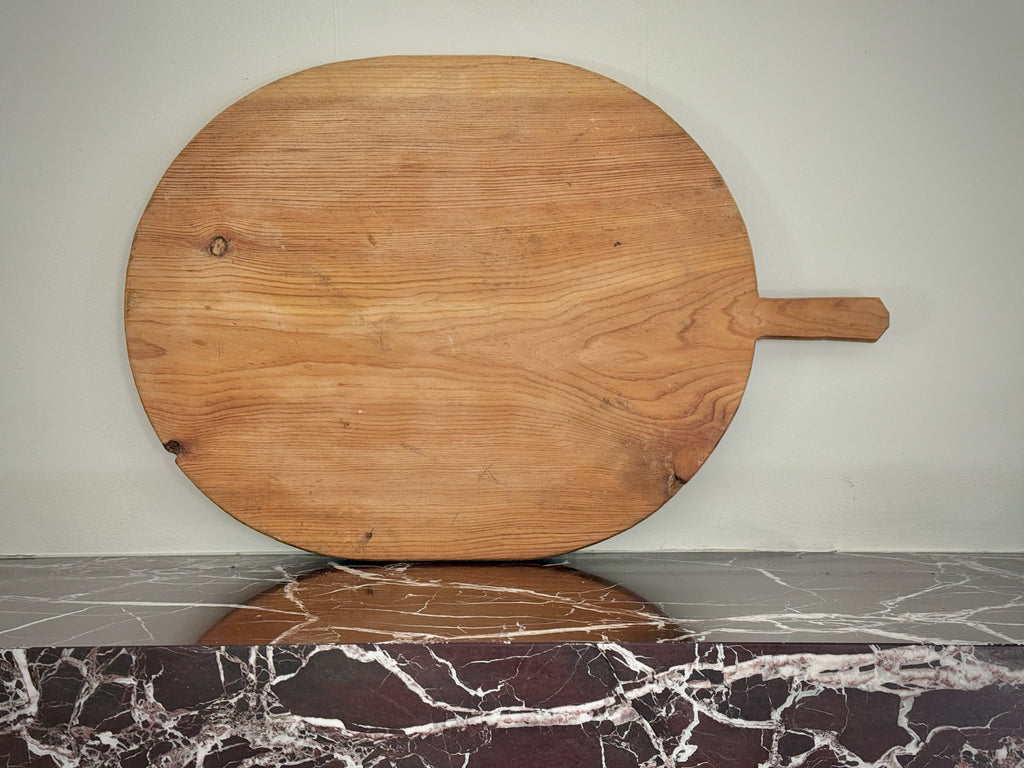 Wooden pizza peel on a marble countertop with a neutral background