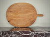 Wooden pizza peel on a marble countertop with a neutral background