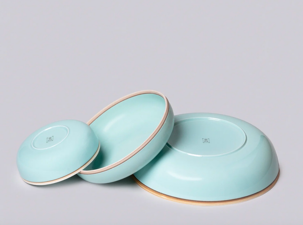 Three light blue ceramic bowls with gold rims on a gray background