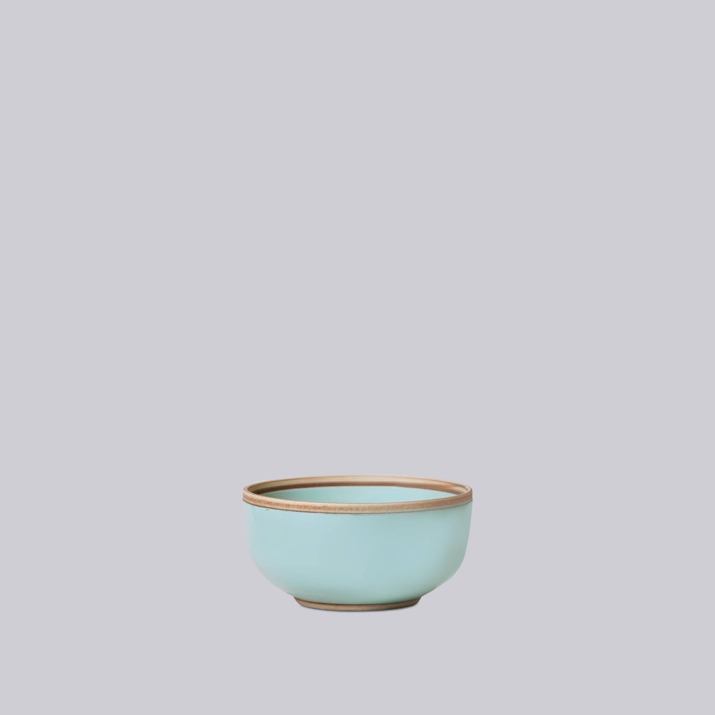 Teal celadon ceramic bowl on a light gray background