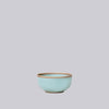 Teal celadon ceramic bowl on a light gray background