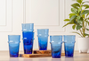 Set of blue tumblers on a wooden cutting board with a plant in the background