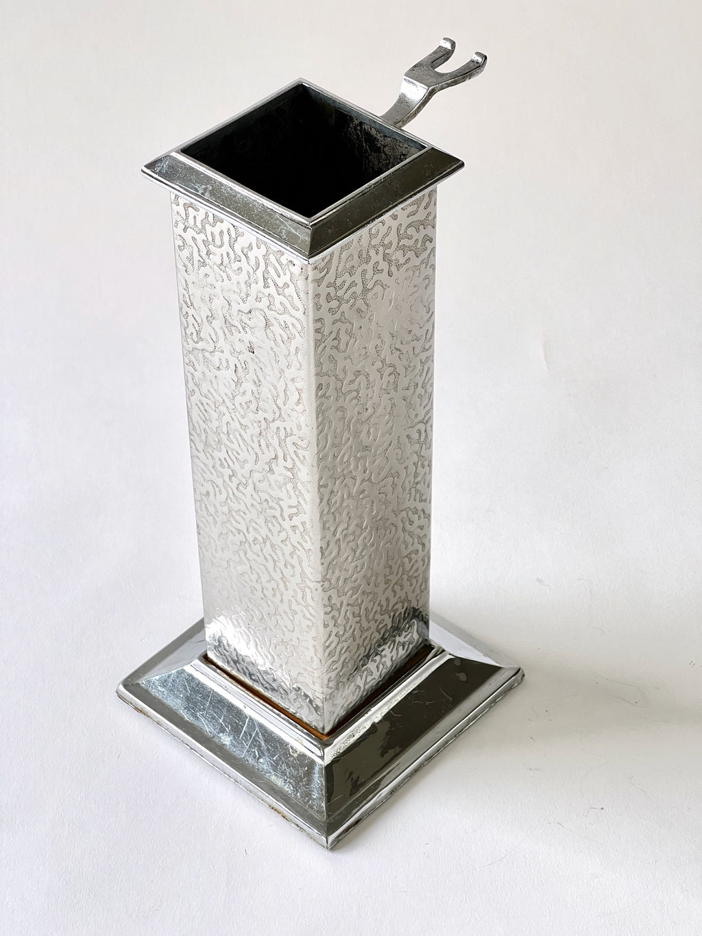 silver tool vase with textured design on a white background