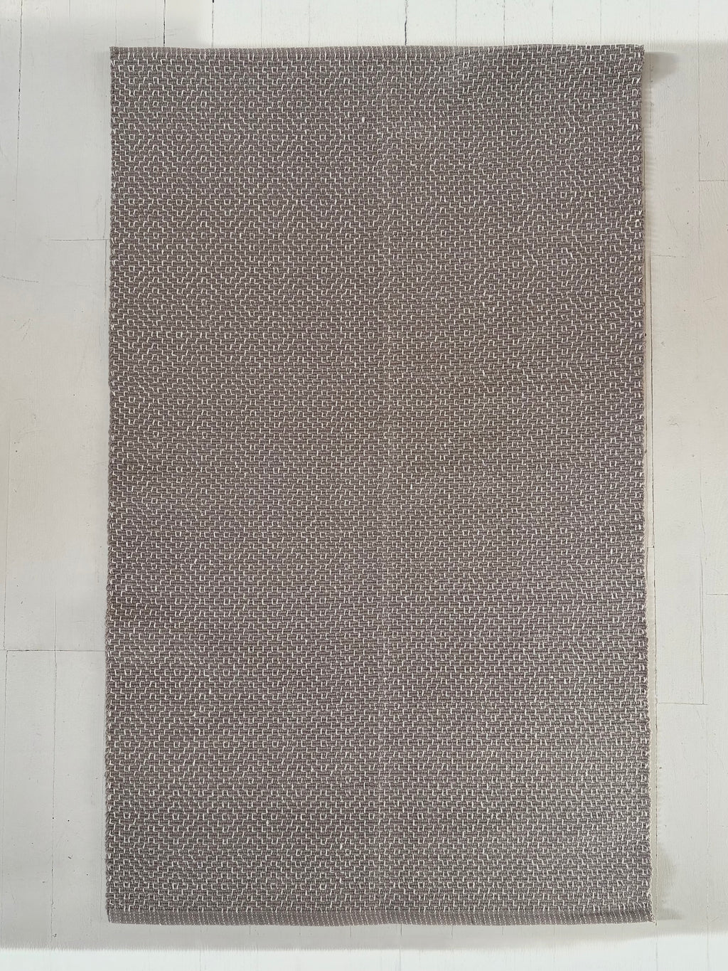 Gray textured cotton rug on a light wooden floor