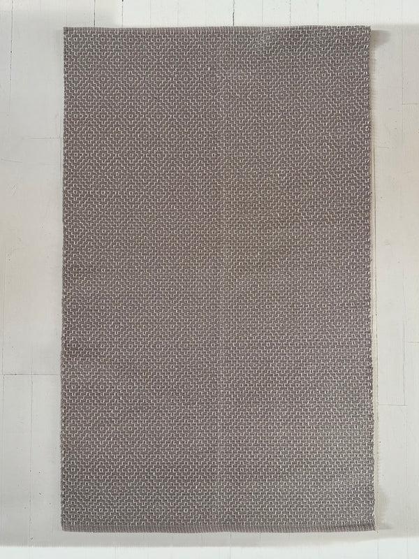 Gray textured cotton rug on a light wooden floor