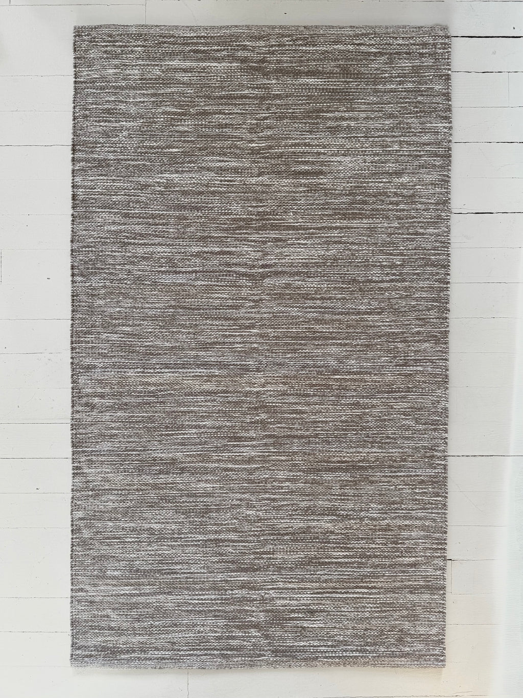 Gray textured area rug on a white wooden floor