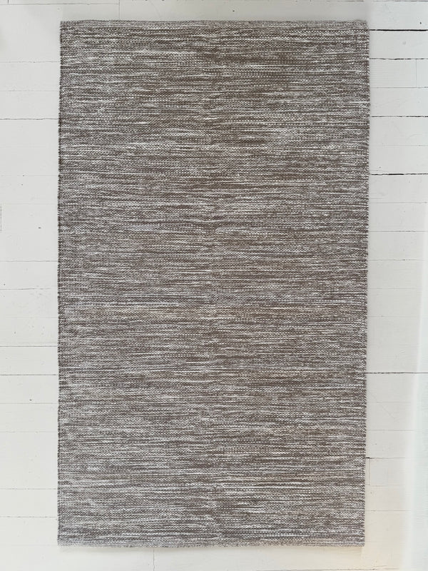 Gray textured area rug on a white wooden floor