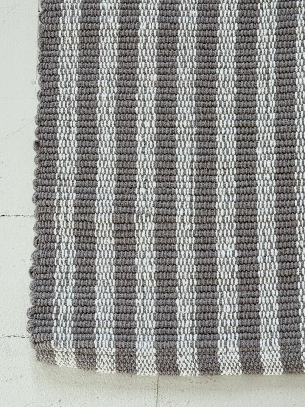 Striped gray and white rug on a light wooden floor