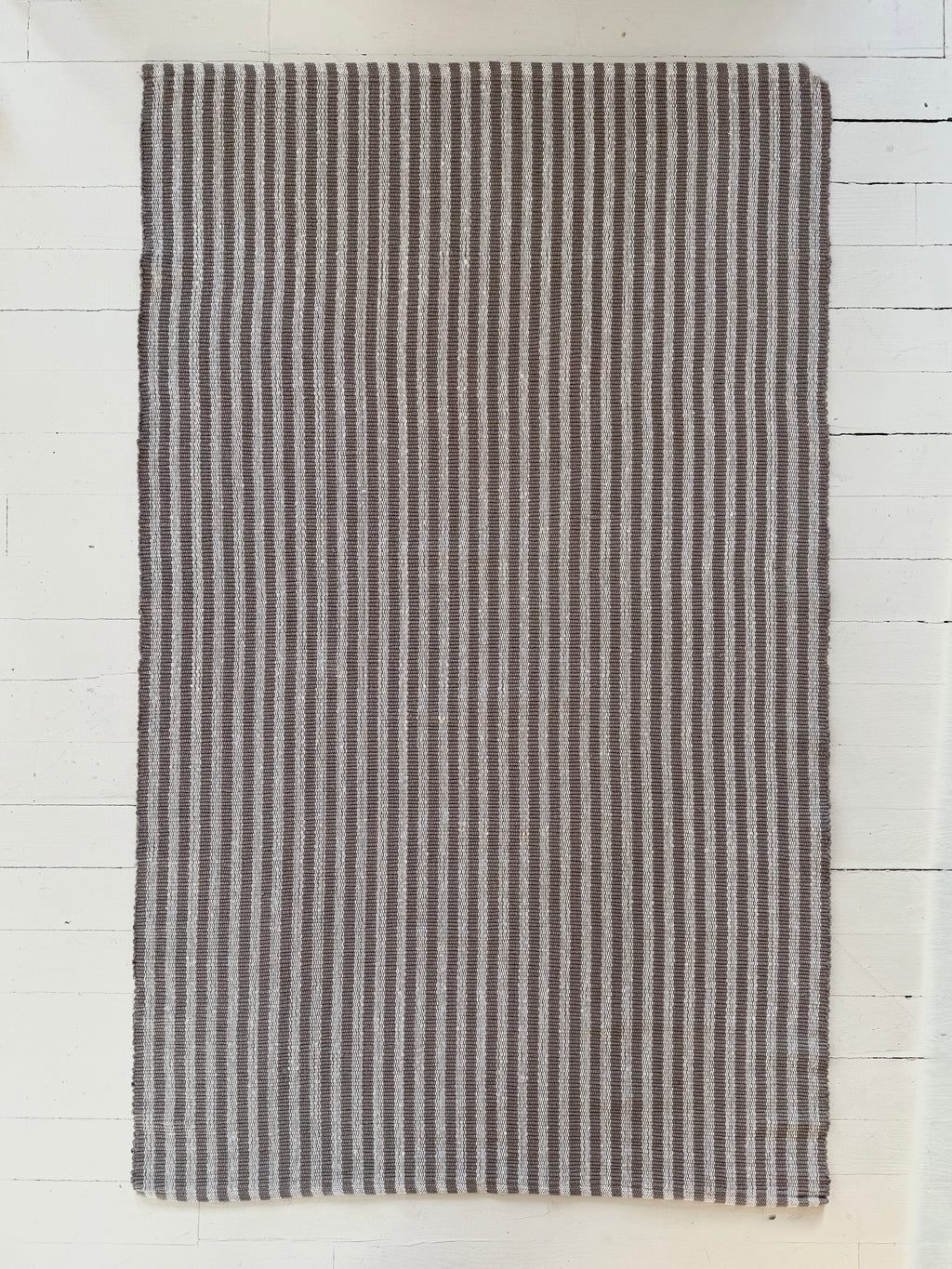 Striped rug with black and white pattern on a light wooden floor