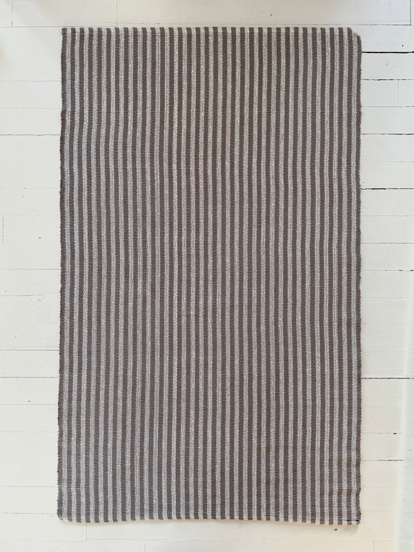 Striped rug with black and white pattern on a light wooden floor