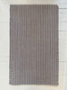 Striped rug with black and white pattern on a light wooden floor