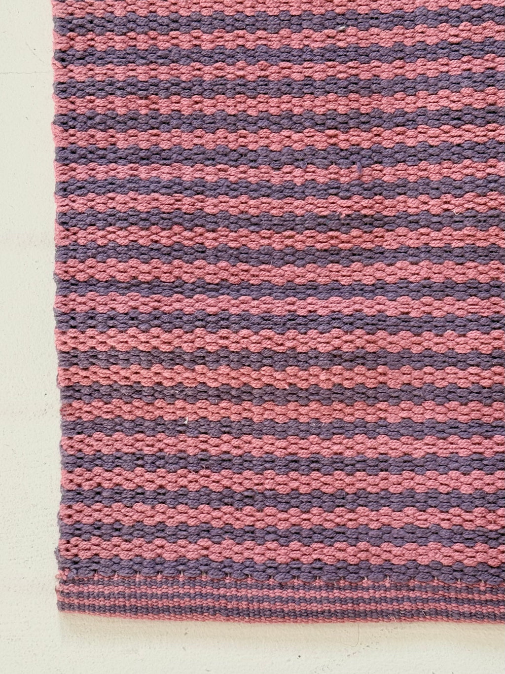 Striped pink and purple rug on a white background