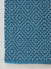 Blue textured cotton rug with geometric pattern on a light wood floor