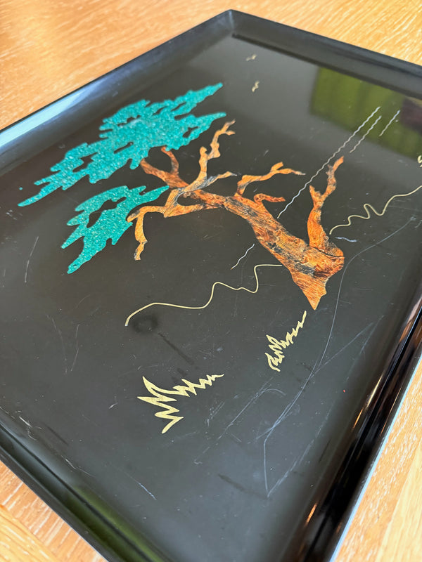 Decorative tray with tree designs in green, orange, and gold on a black background