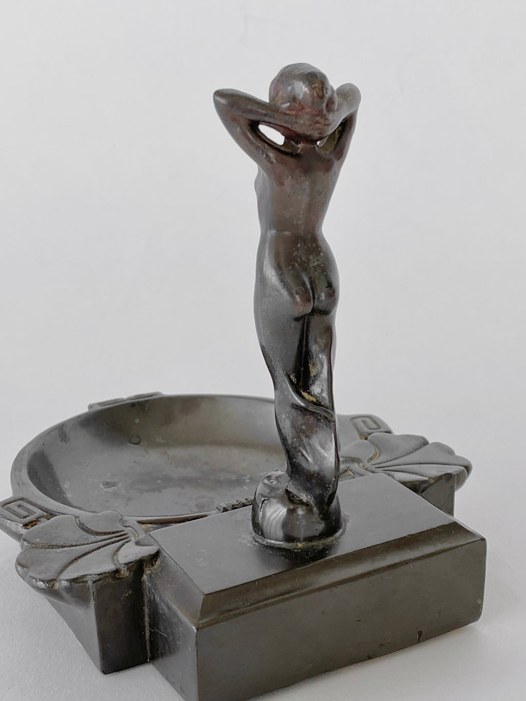 Decorative metal sculpture of a nude figure on a white background