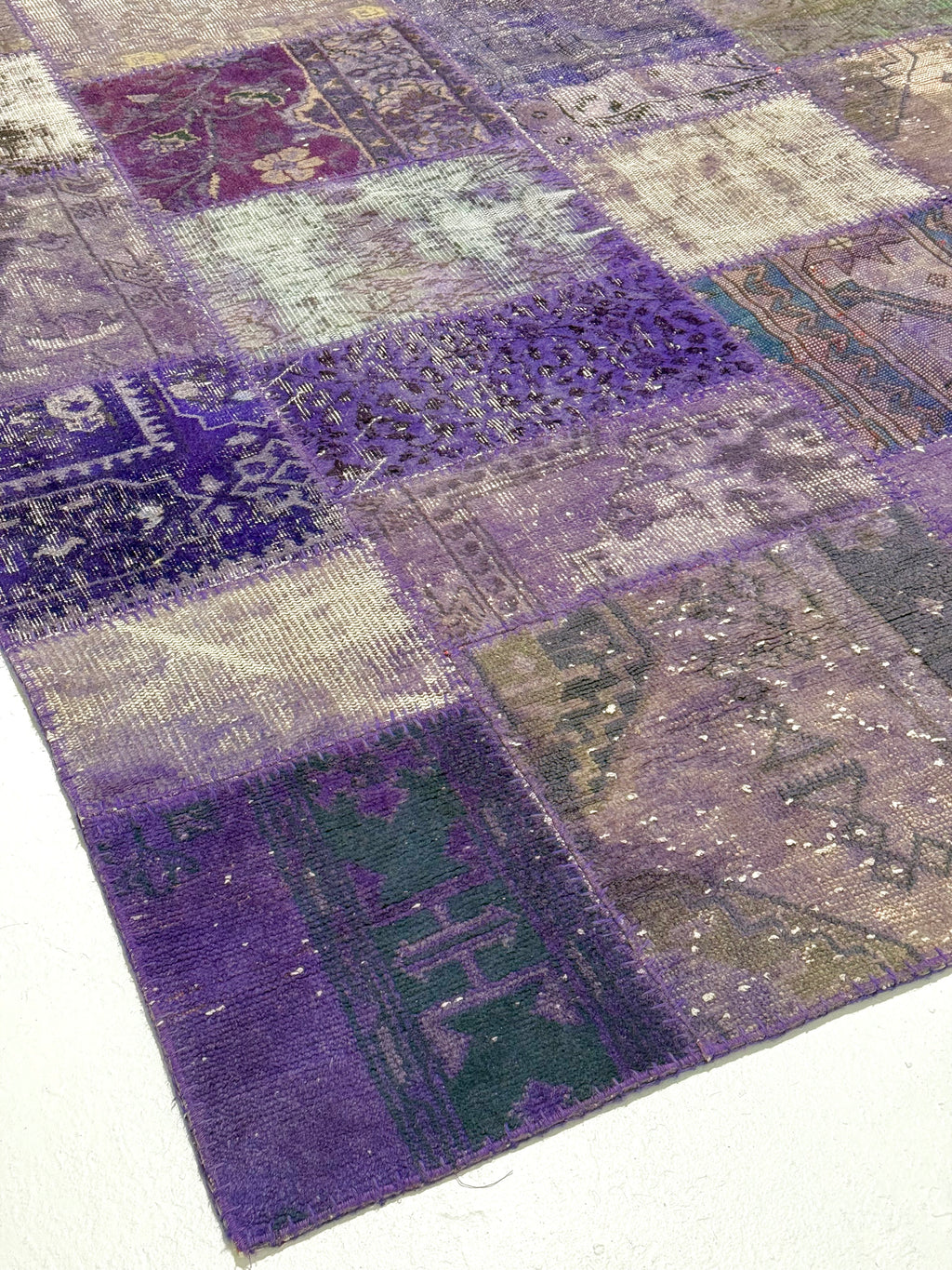 Patchwork rug with purple and gray squares on a white background