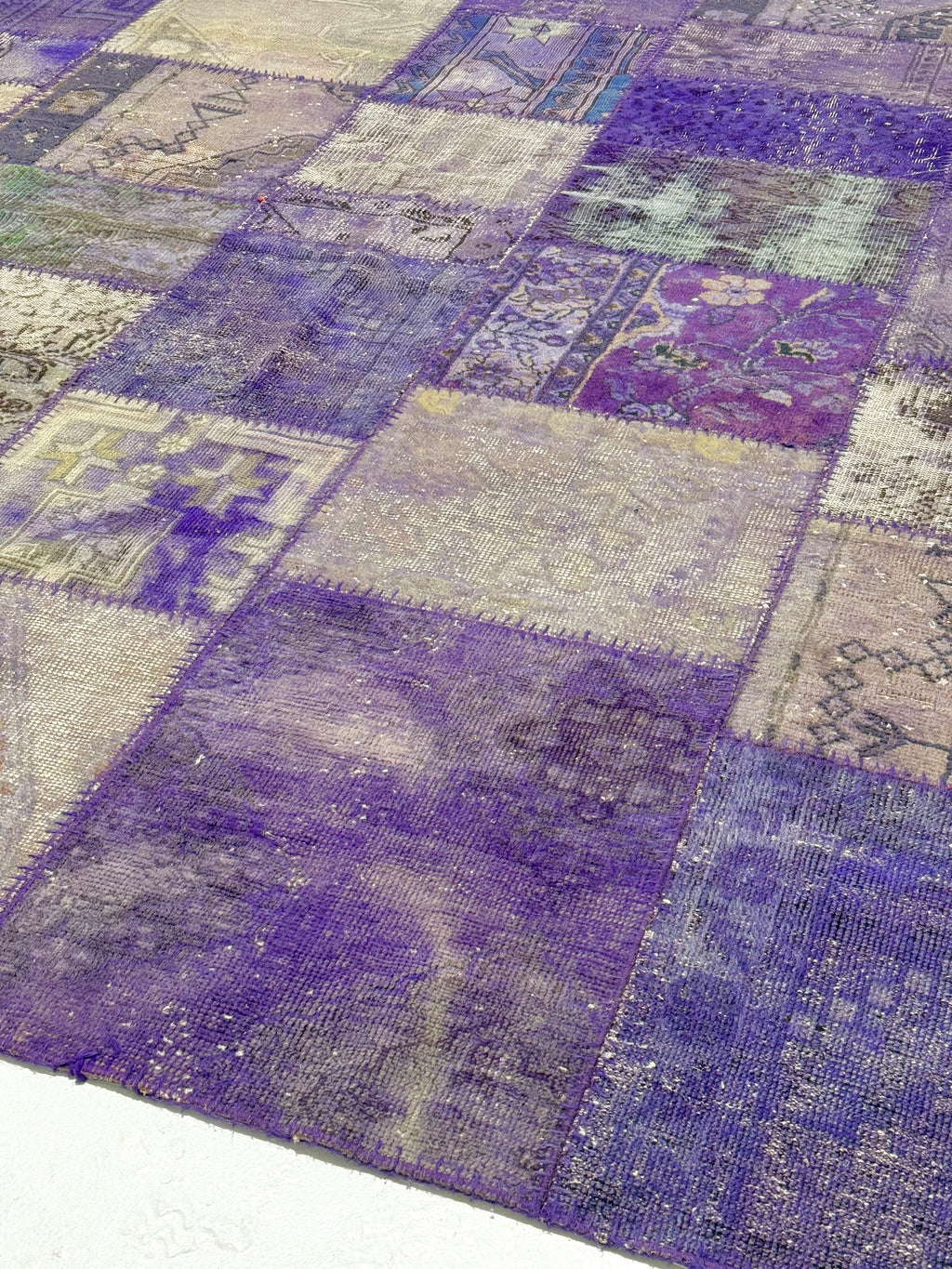 Patchwork rug with purple and gray squares on a white background