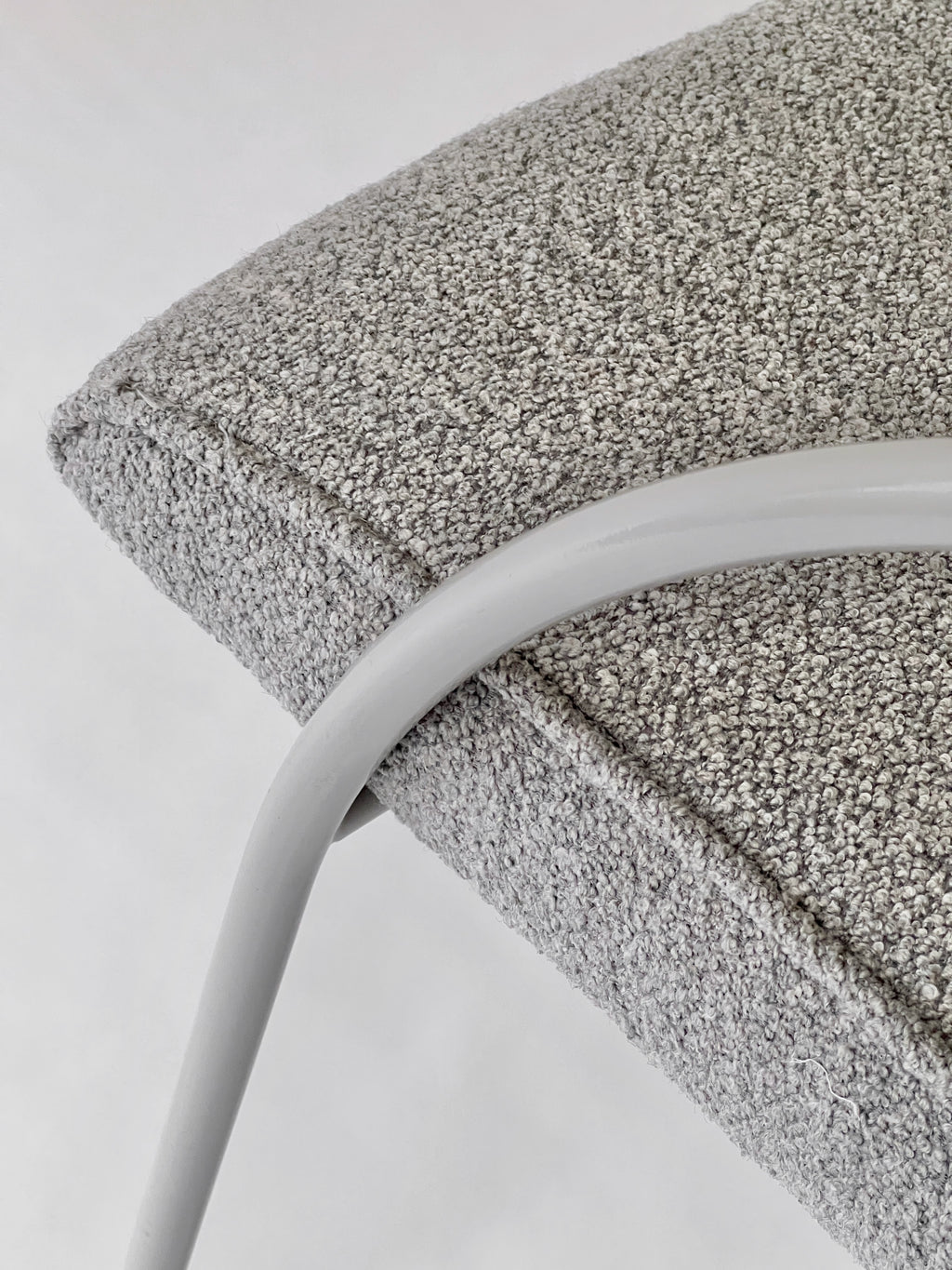 Close-up of a textured gray cushion on a white chair with a white background