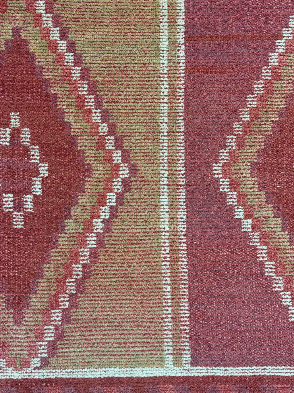 Close-up of a patterned rug with red and beige colors