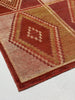 Close-up of a patterned red and beige rug on a light gray background