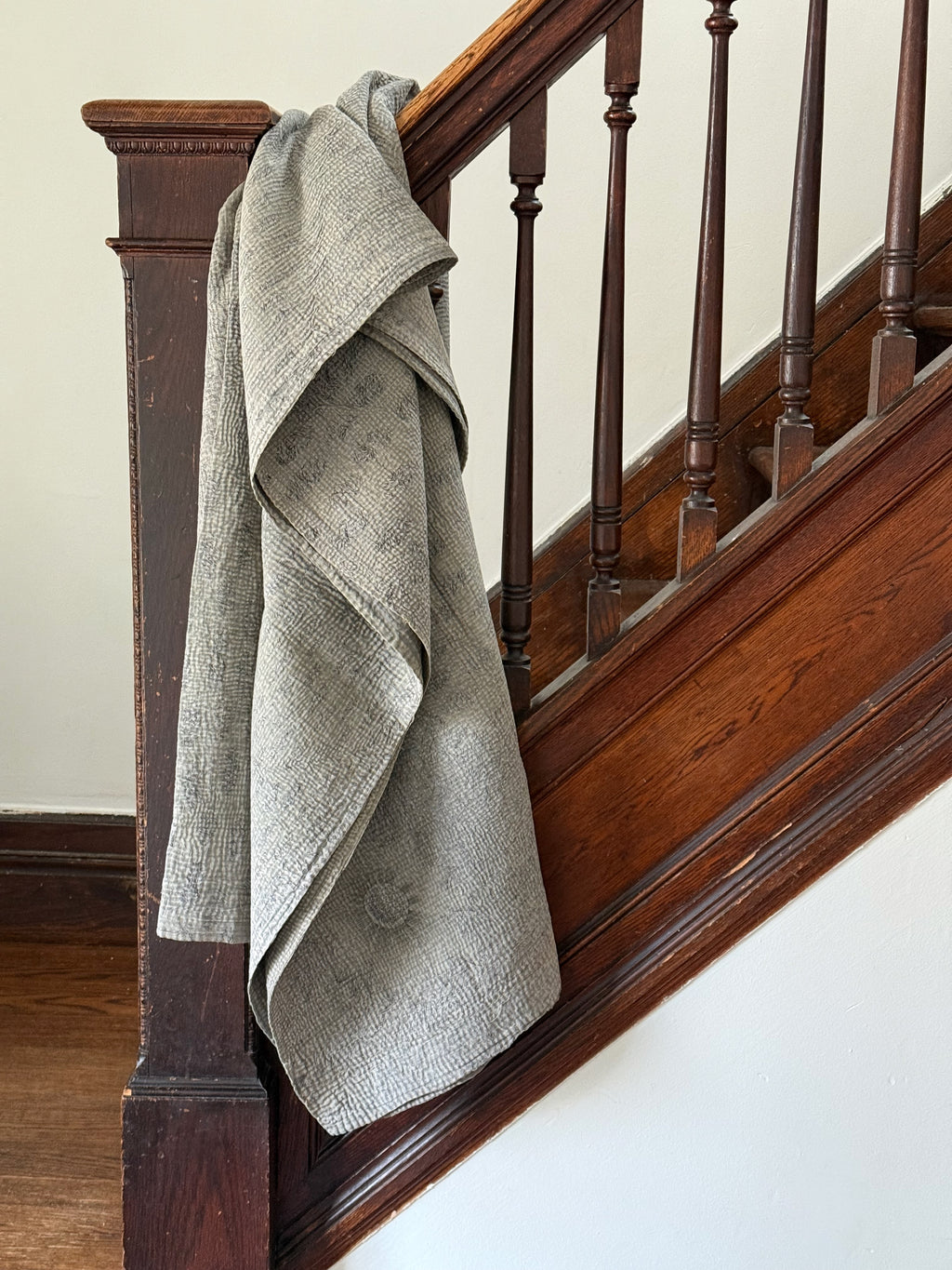 Gray blanket draped over a wooden staircase railing.