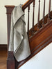 Gray blanket draped over a wooden staircase railing.