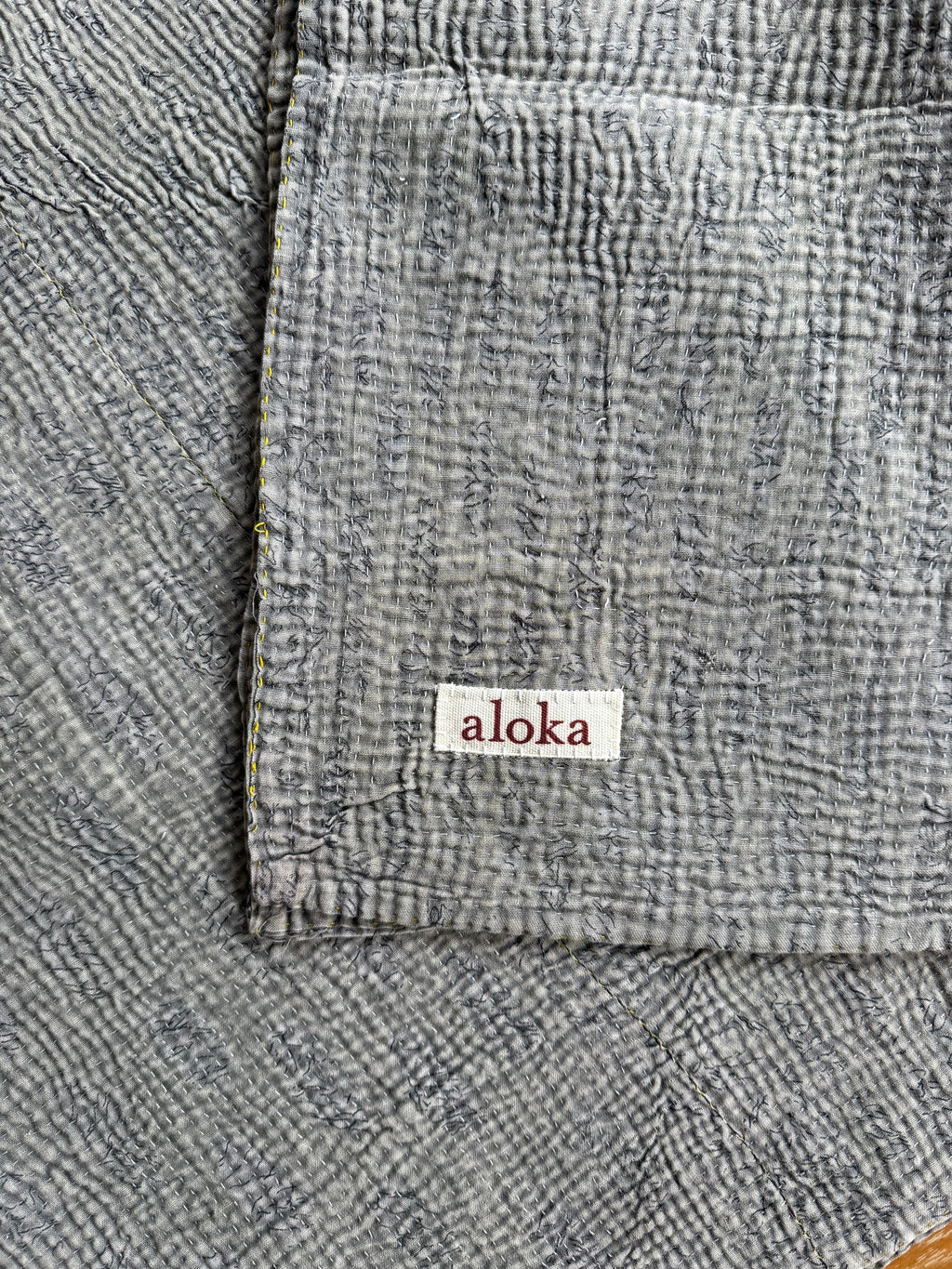Gray textured blanket with 'aloka' label