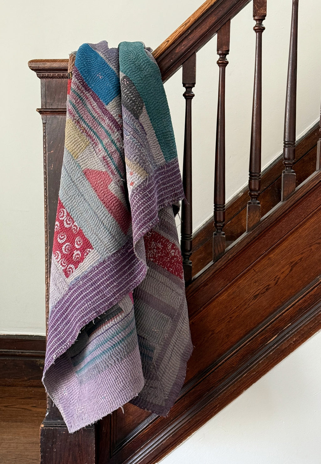 Colorful knitted blanket draped over a wooden staircase