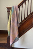 Colorful quilt draped over a wooden staircase rail.