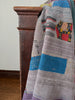 Patchwork quilt draped over a wooden chair against a white wall.