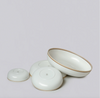 Set of white ceramic bowls with gold rims on a light gray background